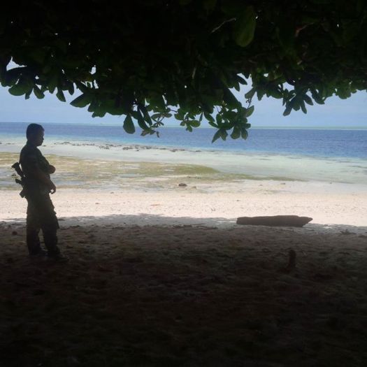 An Army personnel stands guard at Siamil island and can only watch boats go by