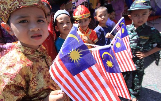 Children in different costumes holding the Malaysia flag - BERNAMA