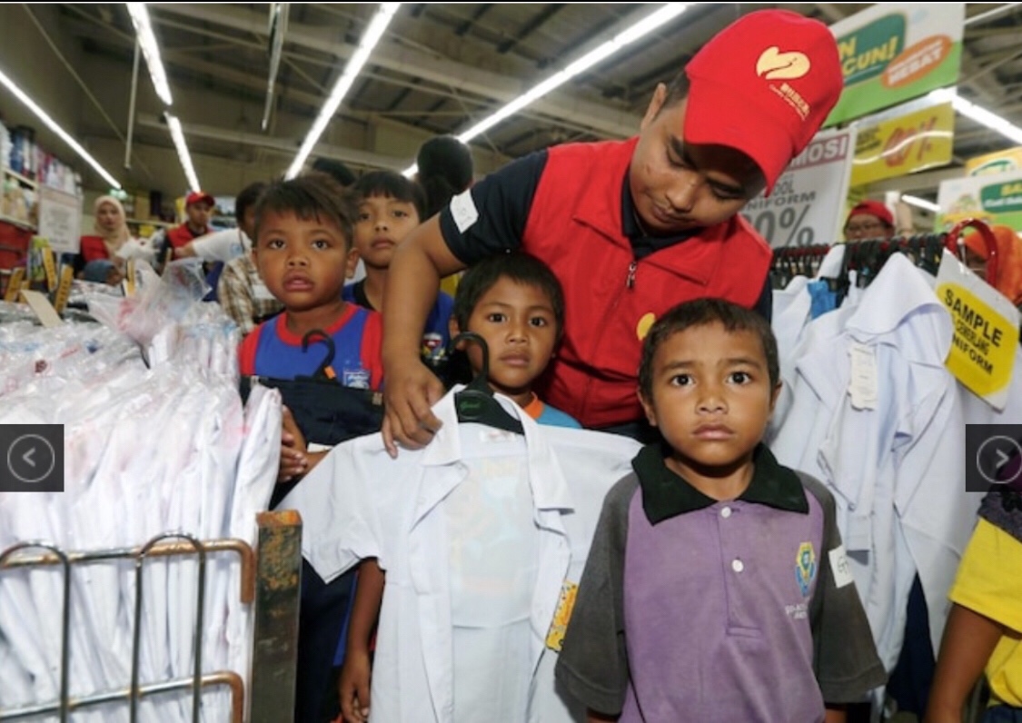 Forest City staff assisting Orang Asli children to choose their school uniform at the Giant Hypermarket in Tampoi (pic courtesy of NSTP/Hairul Anuar Rahim)